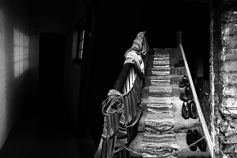 Image of a set of stairs with fabric draping that appear to be leadiung up to the black abyss conveying an intensely spooky feeling.